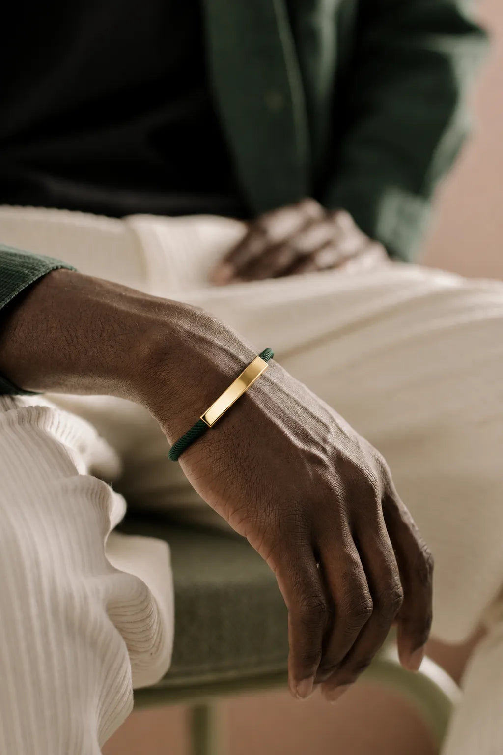 Detalhe da pulseira masculina verde com placa dourada no pulso