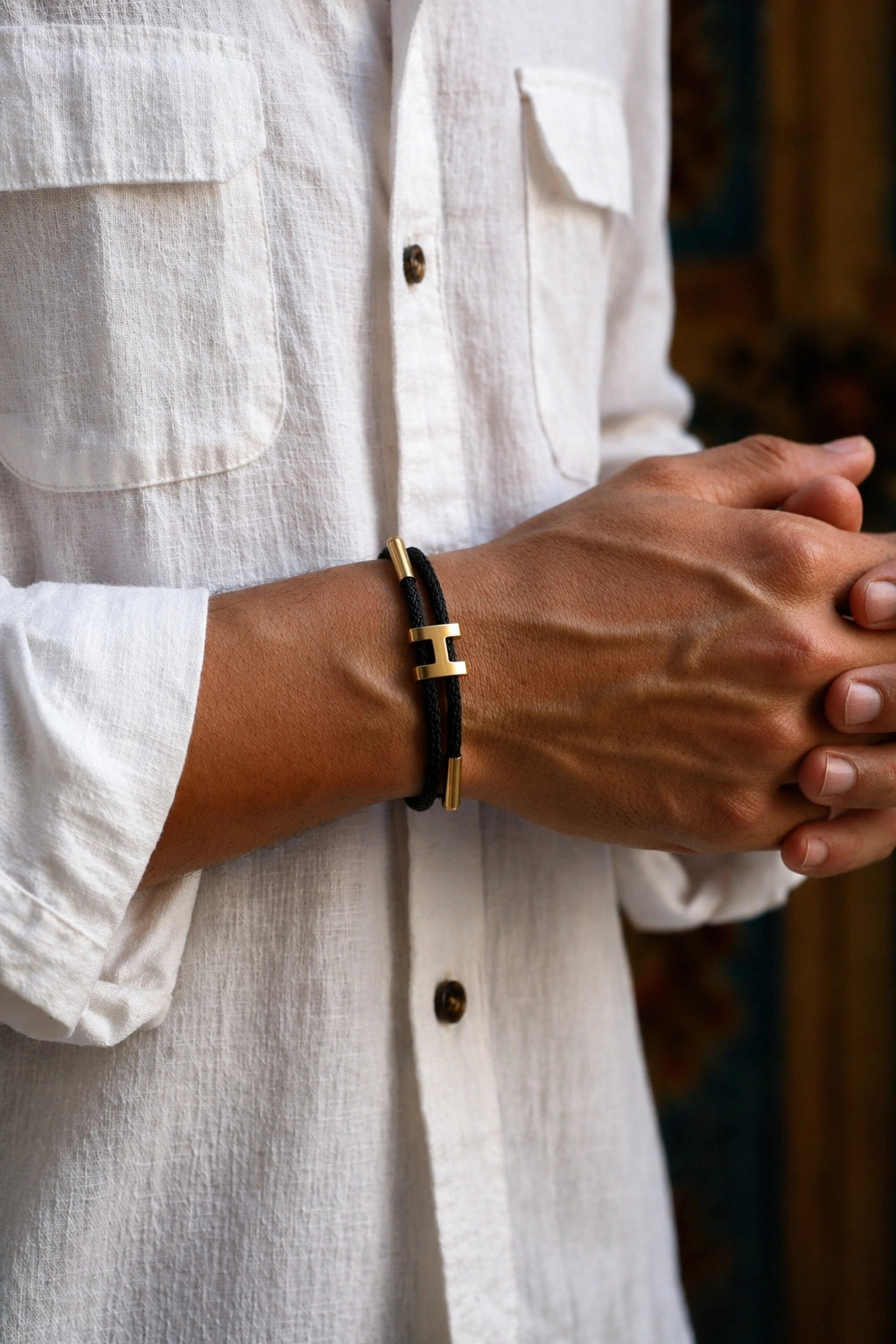 Pulseira Supima H'ills preta no pulso masculino com camisa branca