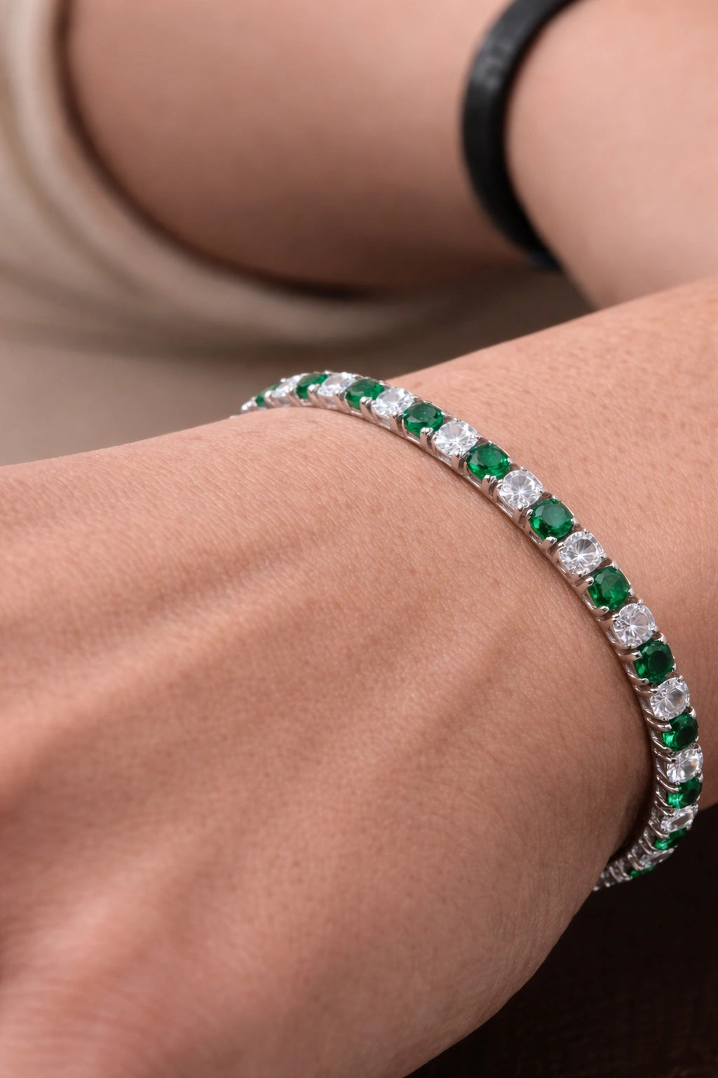 Close da pulseira Aspen Esmeralda com pedras verdes e claras no pulso