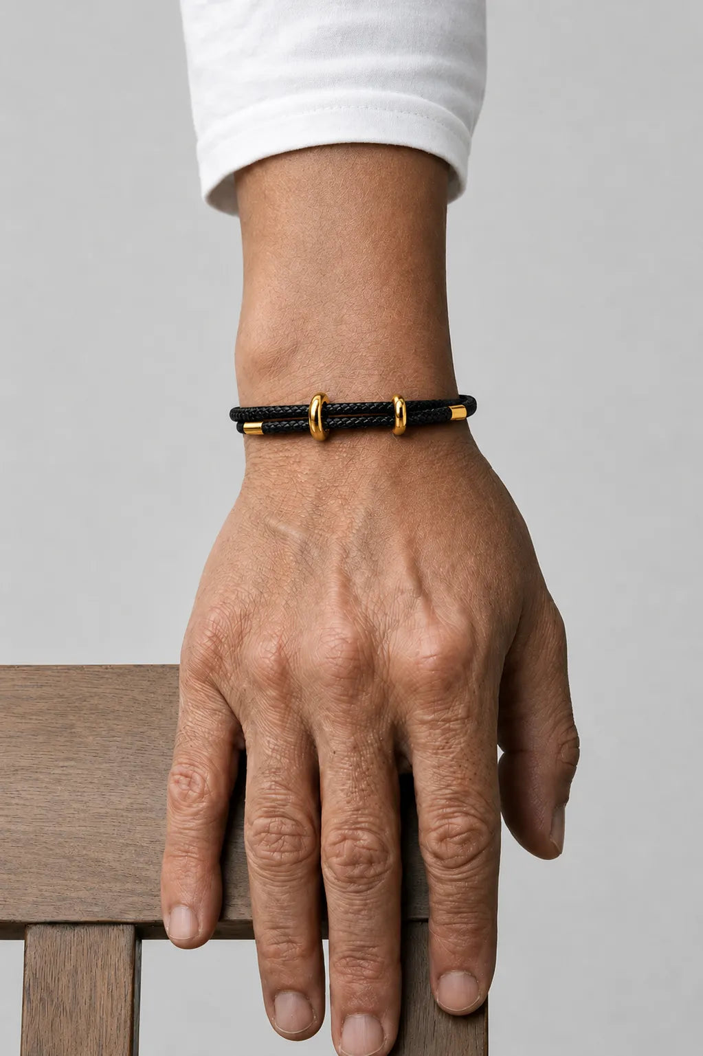 Pulseira de corda preta Supima no pulso com detalhes dourados