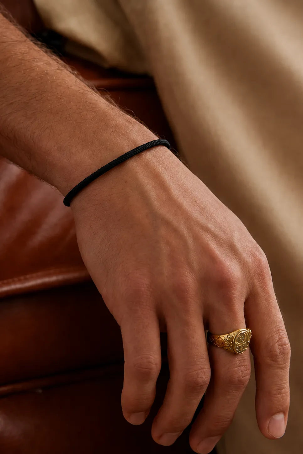 Pulseira Barcelona preta no pulso ao lado de anel dourado