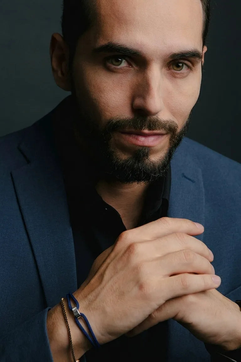 Homem de blazer azul usando pulseira Milan azul com acabamento prateado