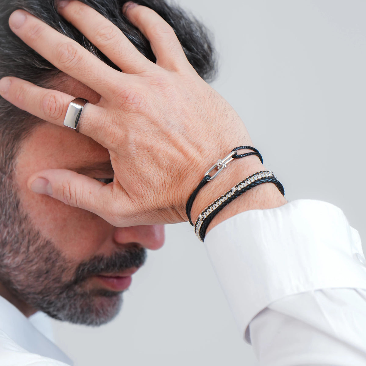Combinação de pulseiras masculinas pretas no pulso com camisa branca